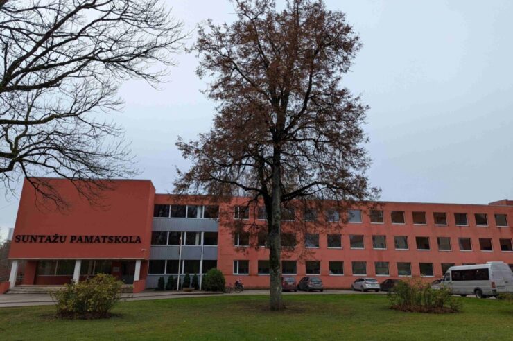 Sarkanīgi oranža Suntažu pamatskolas ēka ar uzrakstu 